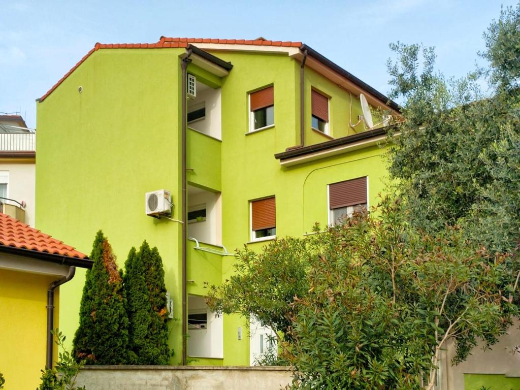 un edificio verde lima con árboles delante de él en Rafael Apartments, en Medulin
