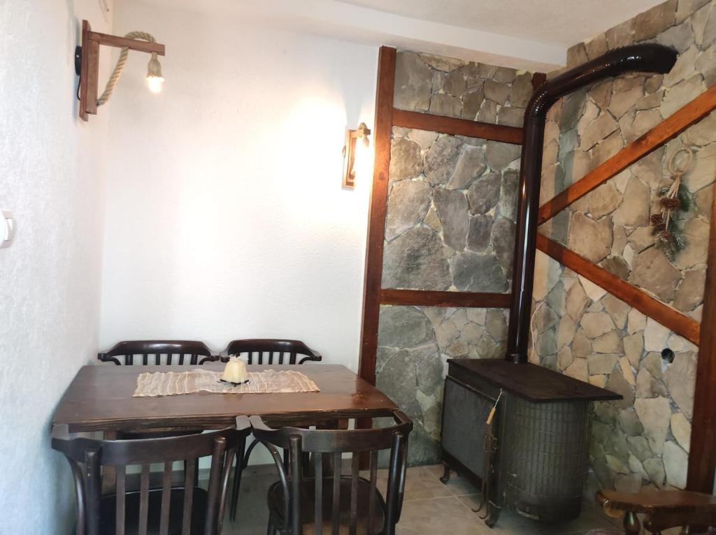 a dining room with a table and chairs and a stone wall at Vila Fantastico in Skopje