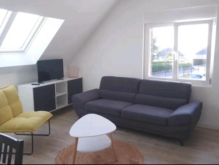 ein Wohnzimmer mit einem Sofa und einem TV in der Unterkunft Maison au calme in Erquy