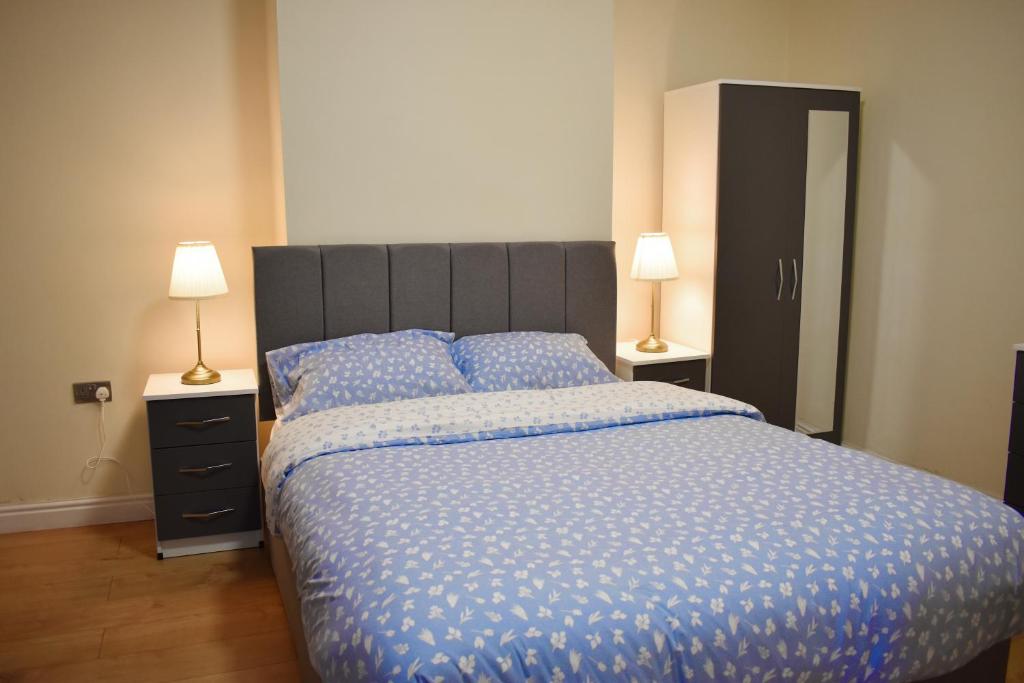 a bedroom with a bed with a blue comforter and two lamps at Pleasant Room nearby edgbaston stadium in Birmingham
