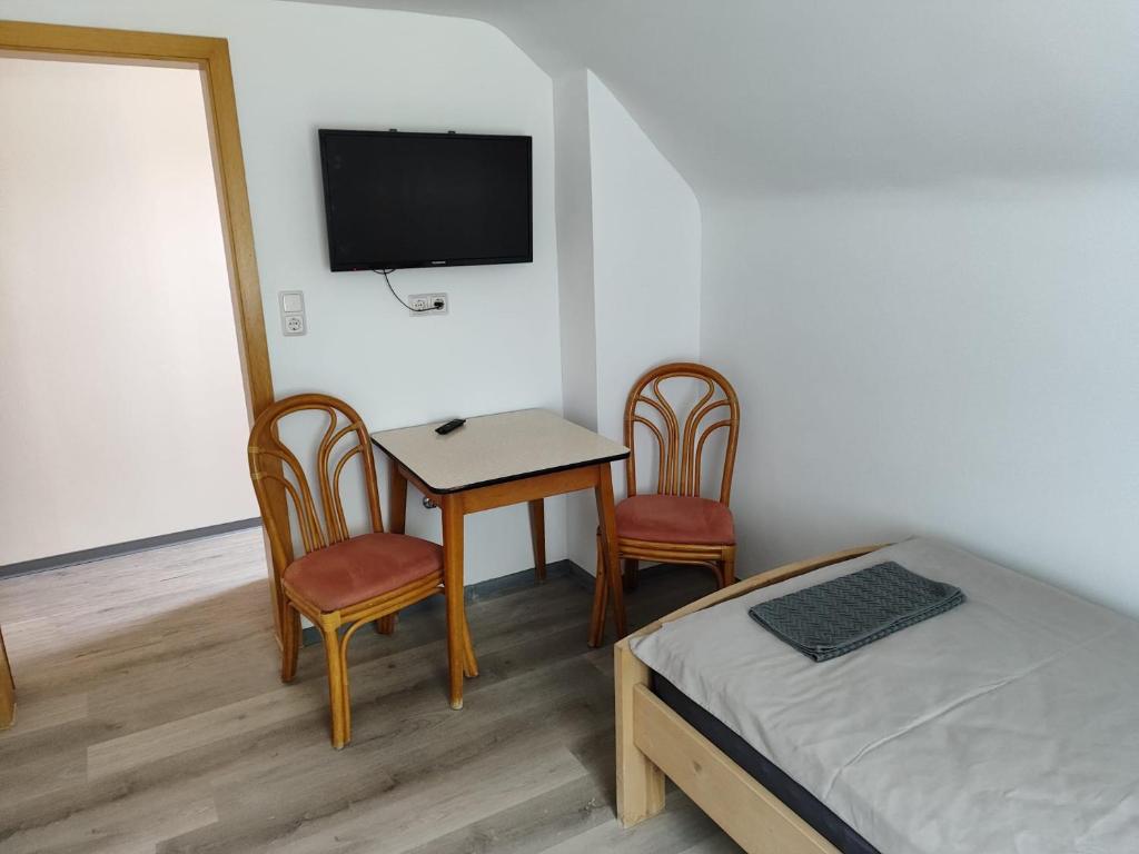 una camera da letto con un tavolo, due sedie e un letto di Apartments zum stillen Winkel a Niederbreitbach