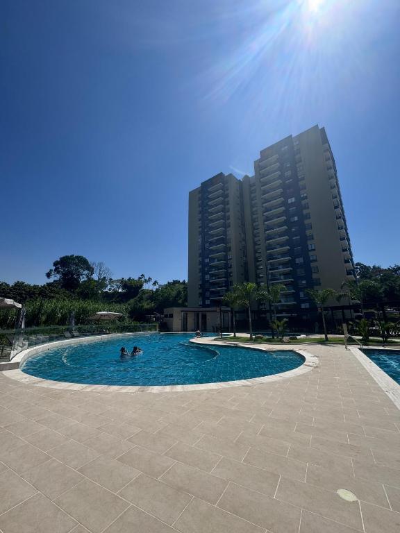 two people swimming in a swimming pool with tall buildings at Luxurious With Private Jacuzzi 3-Bedroom Apartment in Pereira in San Joaquín