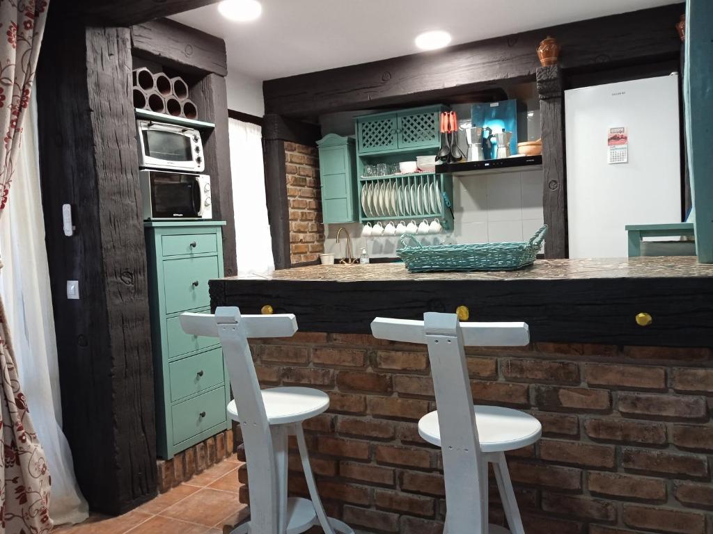a kitchen with green cabinets and two stools at a bar at Casa Rural Montepinar in El Bosque