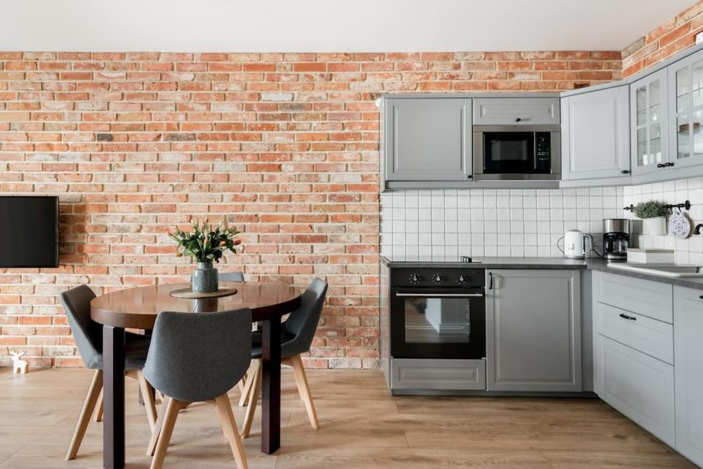 una cucina con tavolo e muro di mattoni di Gdańsk Apartment with Sunny Balcony a Danzica