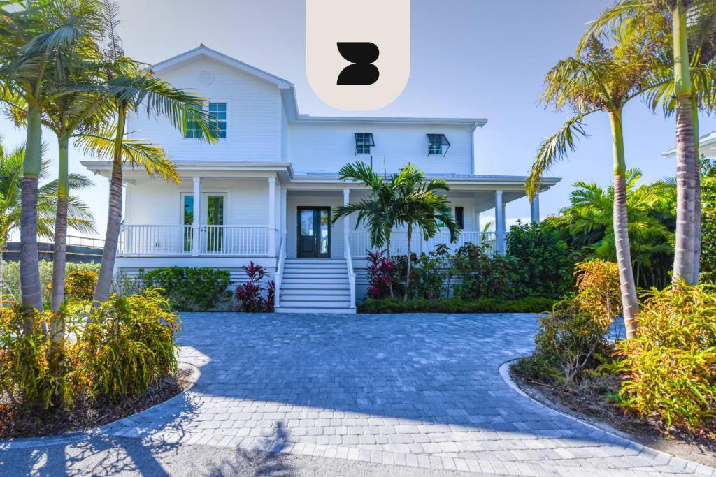 a white house with palm trees and a driveway at Sophisticated Sunsets by Brightwild-Pool & Dock! in Key West
