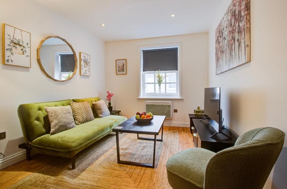 a living room with a green couch and a table at Elegant 1 Bedroom Flat in Brentwood