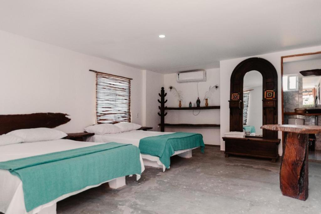 a bedroom with two beds and a table and a mirror at La Triada in Ríohacha