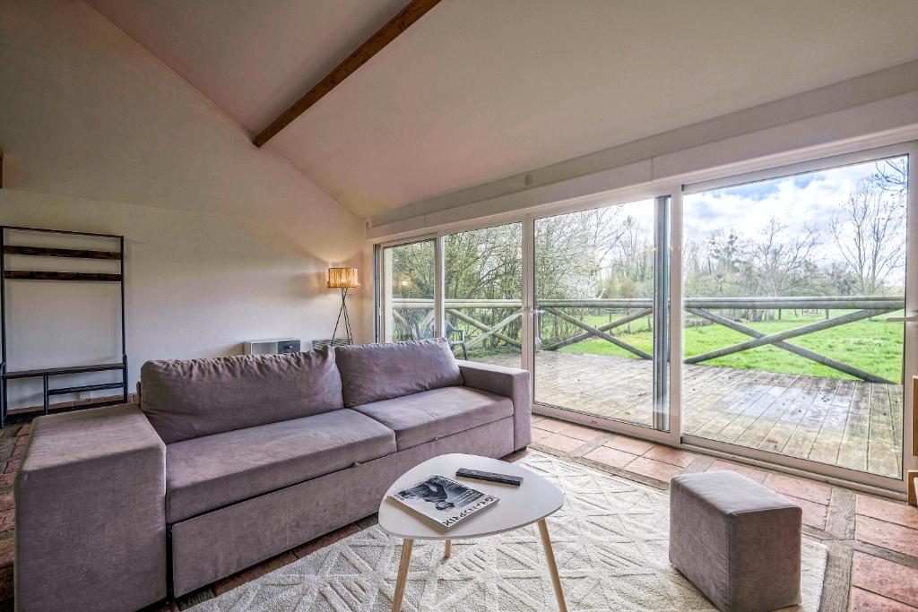 un salon avec un canapé et une grande fenêtre dans l'établissement Cottage les Ecuries, pleine nature, proche Disney-Paris, à Saint-Germain-sur-Morin