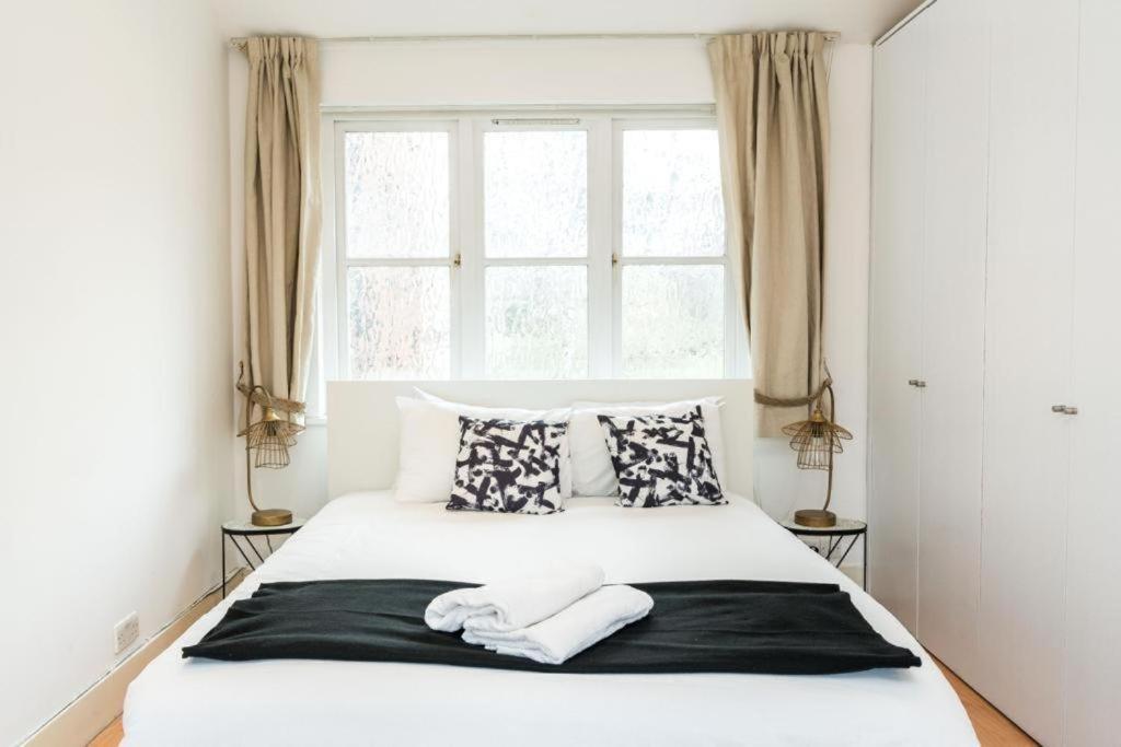 a bedroom with a large white bed with pillows and a window at Comfortable Family Villa in London