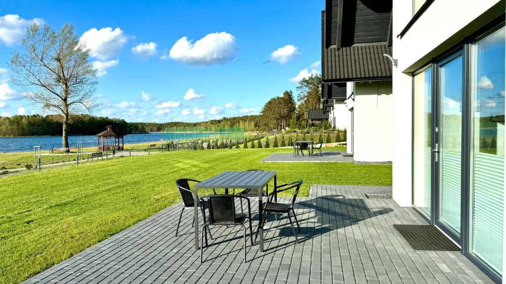 - une table et des chaises sur une terrasse avec vue sur l'eau dans l'établissement Domki nad jeziorem u Izy, à Kiedrowice