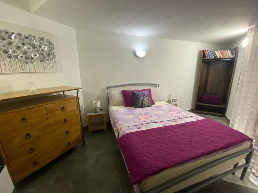 - une chambre avec un lit violet et une commode dans l'établissement Birgu Studio Maisonette, à Il-Birgu