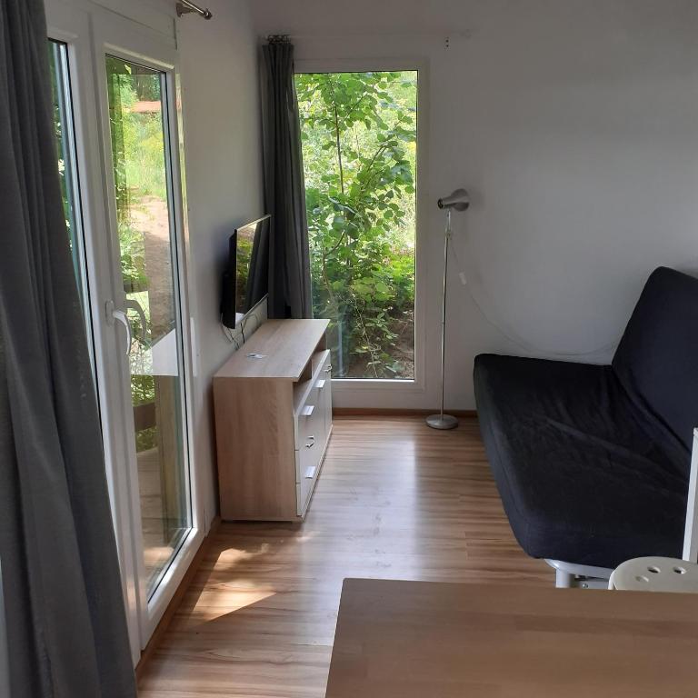 uma sala de estar com uma televisão, uma cadeira e uma janela em domek na skarpie em Ruciane-Nida