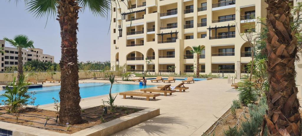 ein Hotel mit einem Pool und Bänken vor einem Gebäude in der Unterkunft Lovely studio Al-Dau Heights in Hurghada