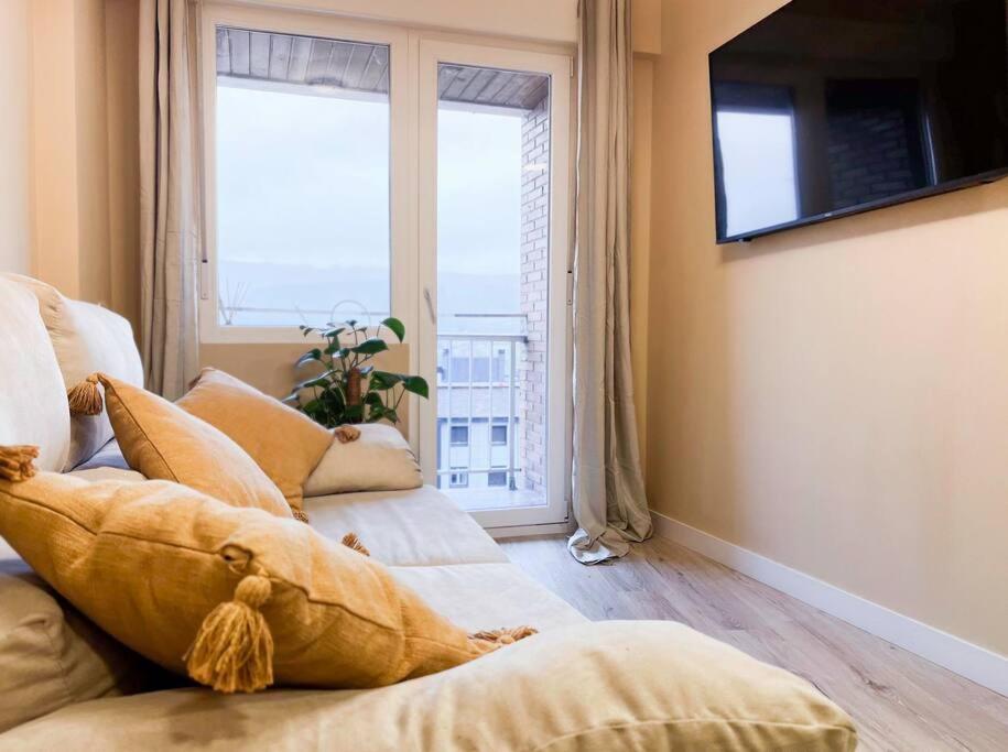 sala de estar con 2 camas y ventana grande en Acogedor y moderno apartamento, en Zamudio
