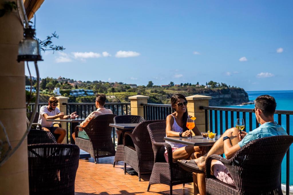 een groep mensen die aan een tafel op een patio zitten bij Hotel Rocca Della Sena in Tropea