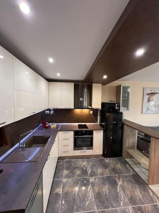 eine Küche mit weißen Schränken und einem schwarzen Kühlschrank in der Unterkunft Tei-Zi apartments in Burgas City