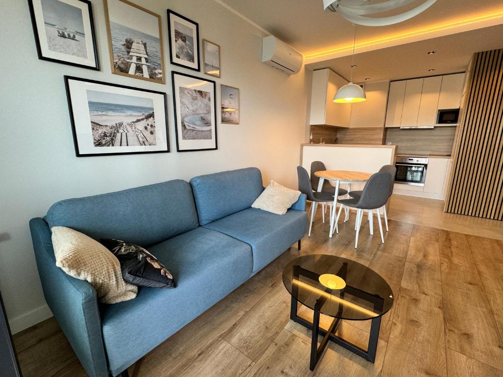 a living room with a blue couch and a table at Apartament nad morzem BALTEA VIEW in Gdańsk