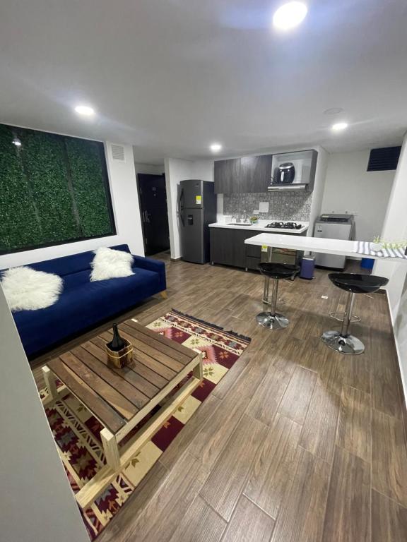 ein Wohnzimmer mit einem blauen Sofa und einer Küche in der Unterkunft Apartaestudio Verum LV - Modelia in Bogotá