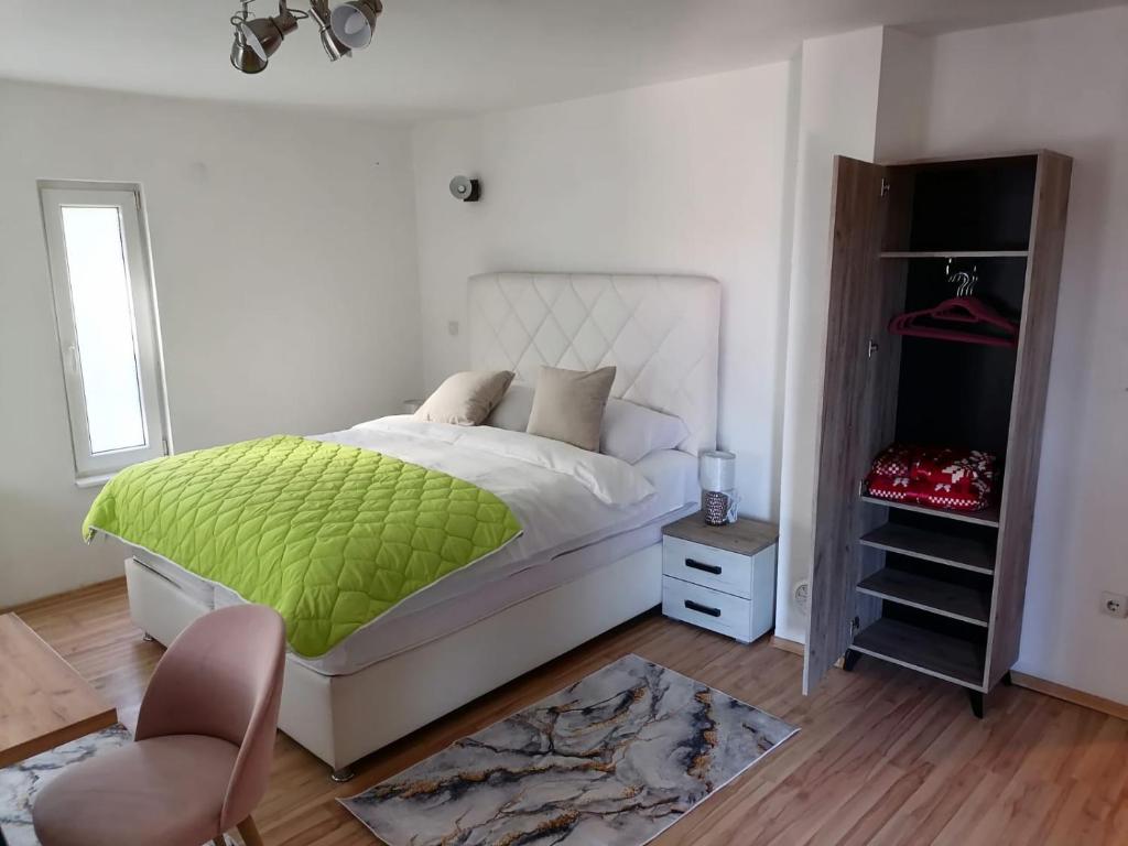 1 dormitorio con 1 cama con manta verde y silla en Sarajevo Holiday Apartments 1, en Sarajevo