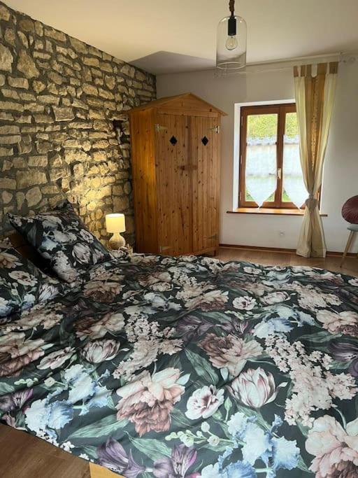 a bedroom with a large bed with a floral blanket at le Gîte de Marie Ray Sur Saône in Ray-sur-Saône