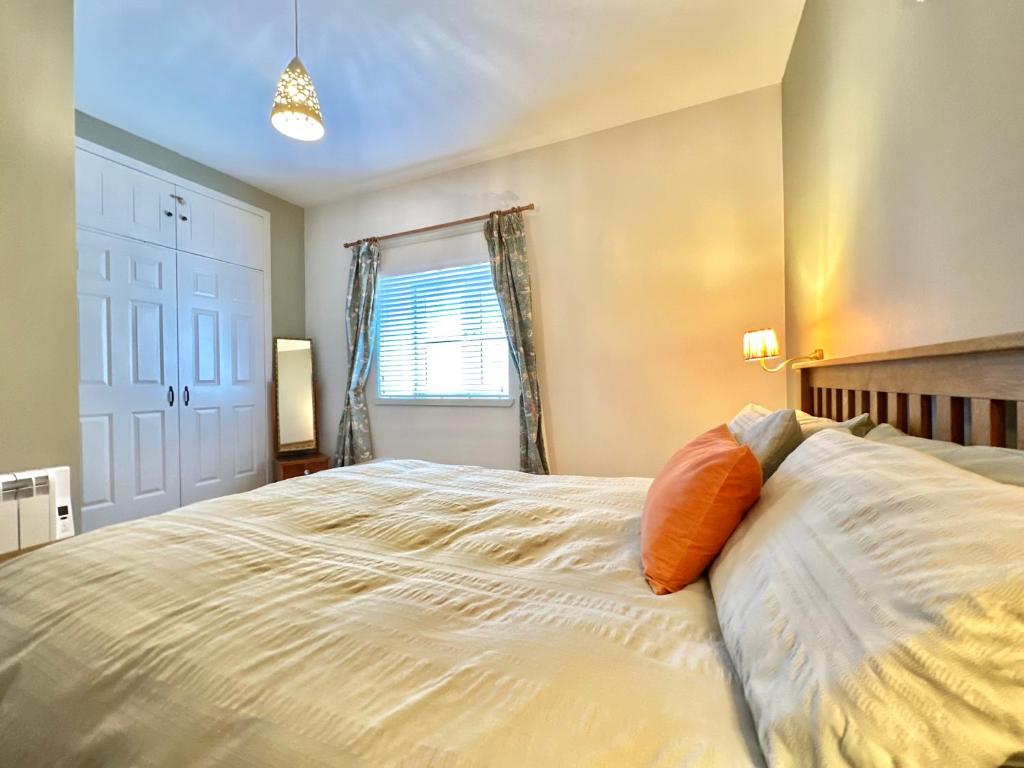 1 The Cairn Kilmartin - Beautiful Victorian Flat, Pet Friendly في Kilmartin: غرفة نوم بسرير ابيض كبير مع وسادة برتقال