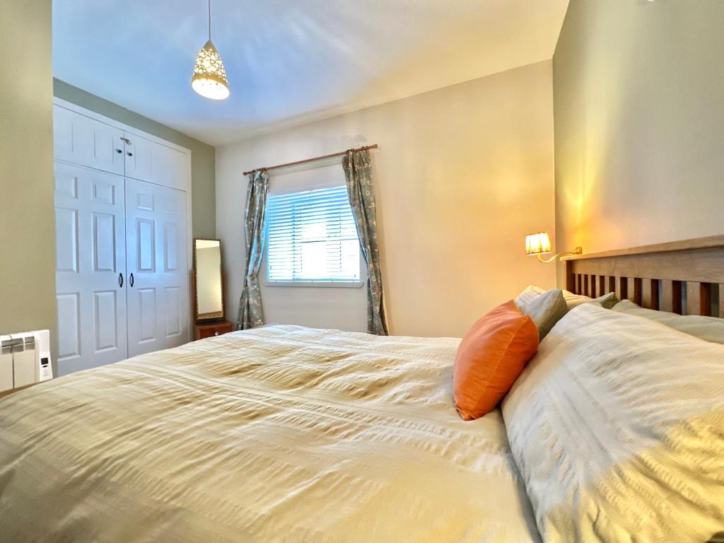 a bedroom with a large white bed with an orange pillow at 1 The Cairn Kilmartin - Beautiful Victorian Flat, Pet Friendly in Kilmartin