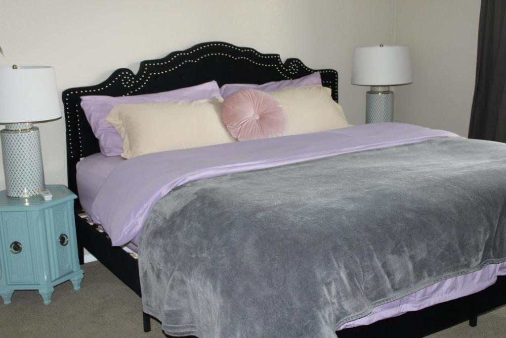 a bedroom with a large bed with purple sheets and pillows at Charming Retreat in heart of Amarillo in Amarillo