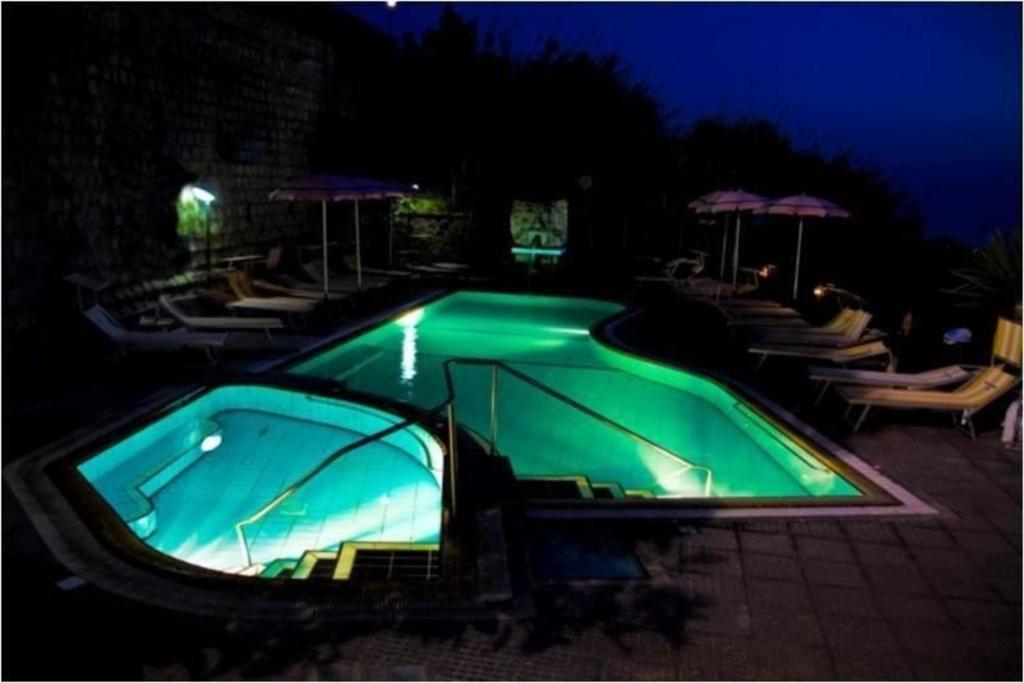 - une piscine verdoyante avec des chaises et des parasols la nuit dans l'établissement Ferienwohnung für 5 Personen ca 65 qm in Forio, Kampanien Ischia, à Ischia