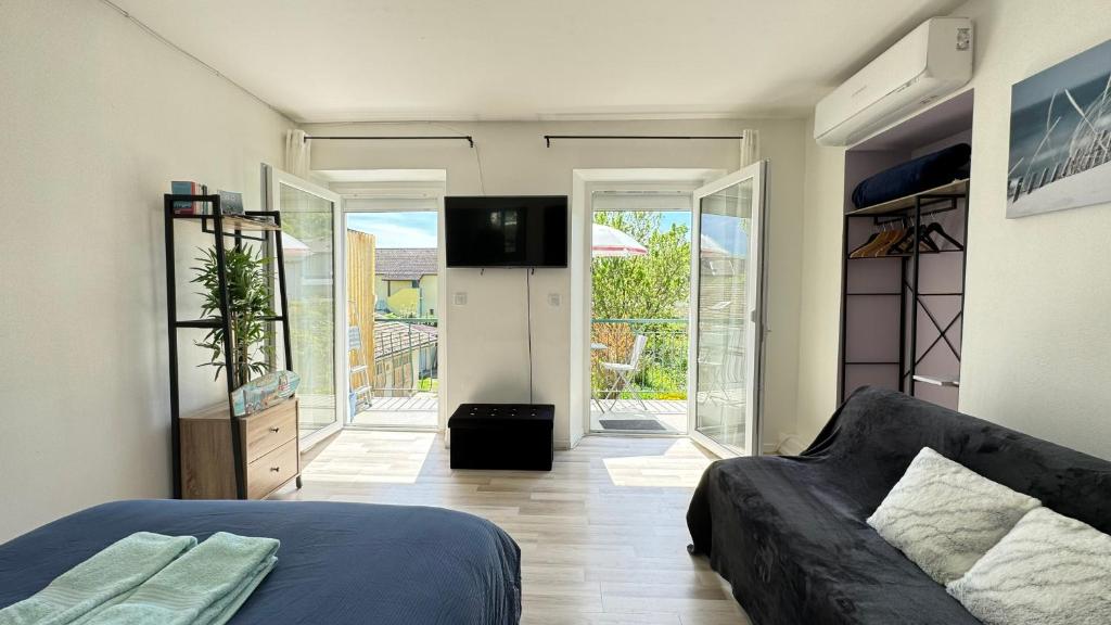 1 dormitorio con 1 cama y TV en una habitación en Charmant T1 entre ville et lac avec balcon, en Aix-les-Bains