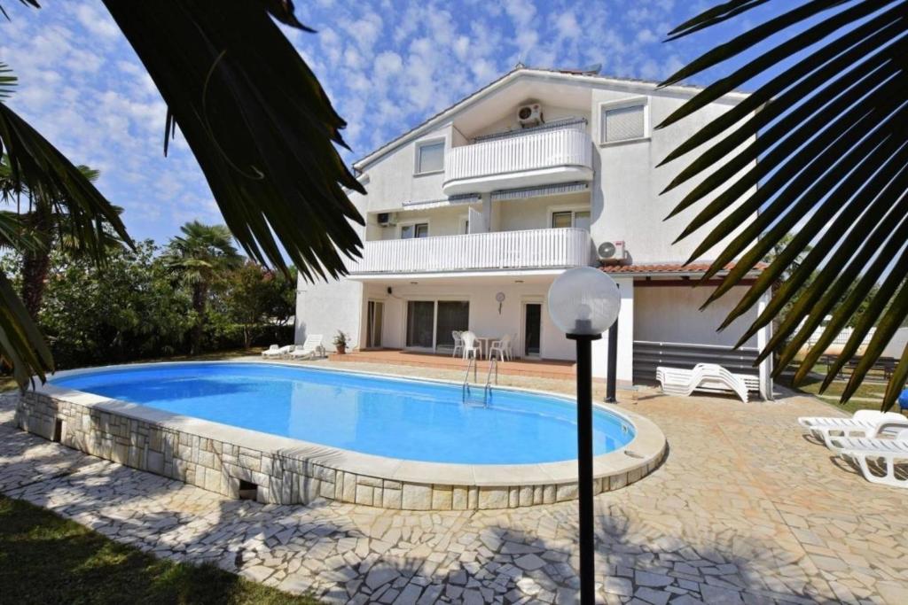 une villa avec une piscine en face d'une maison dans l'établissement Ferienwohnung für 2 Personen ca 18 qm in Poreč, Istrien Istrische Riviera, à Poreč