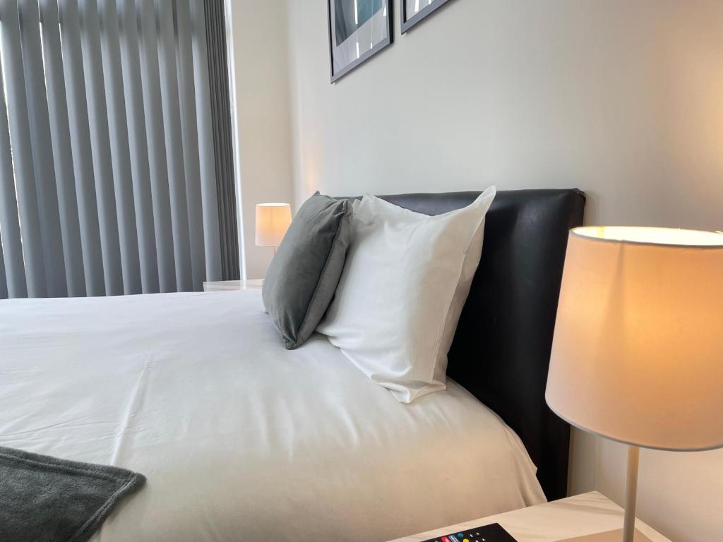 1 dormitorio con 1 cama con almohadas y lámpara en 4 Bedroom 2 Bathroom Shared House - Near BHX and NEC, en Birmingham