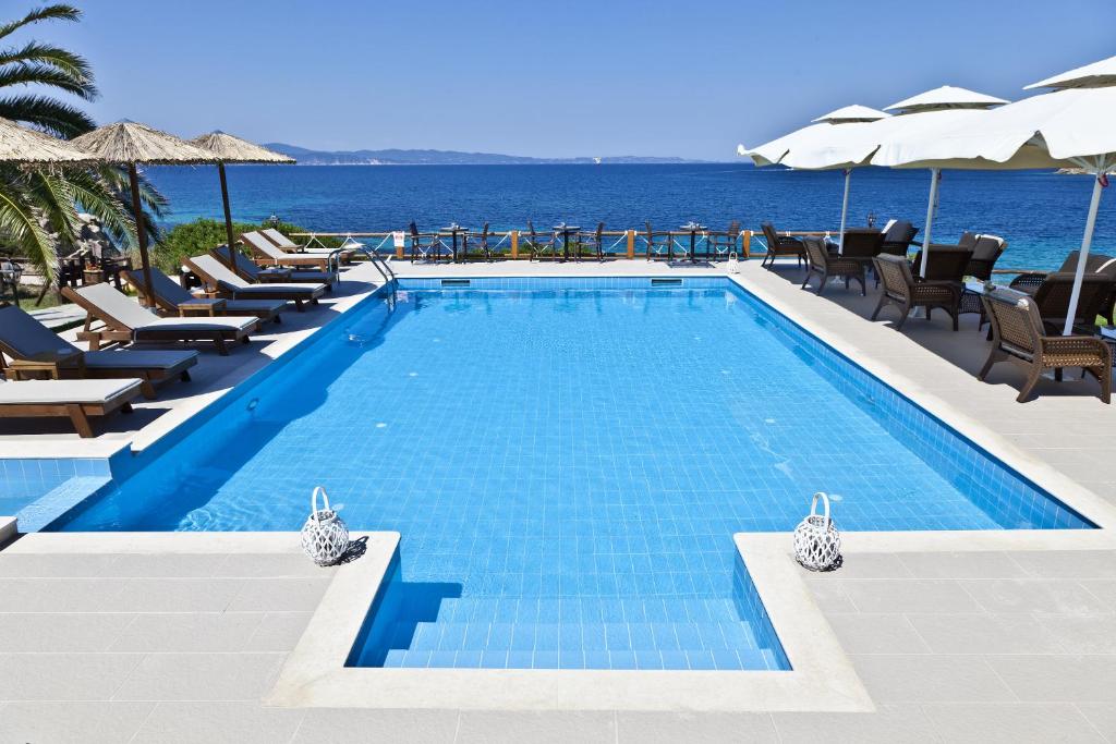 a swimming pool with chairs and the ocean in the background at Barbagiannis House in Ormos Panagias