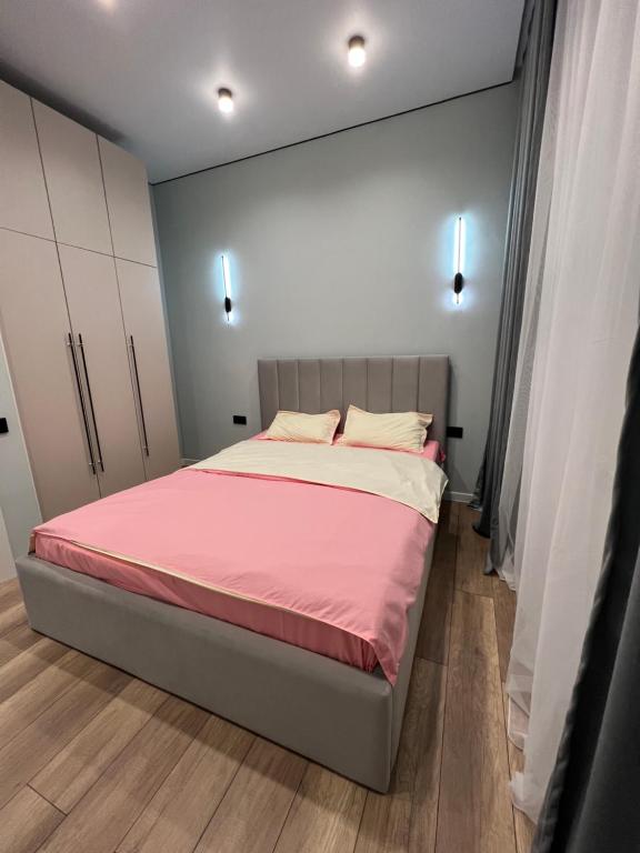 um quarto com uma cama com lençóis cor-de-rosa e brancos em Новая квартира возле Меги и экспо em Taldykolʼ