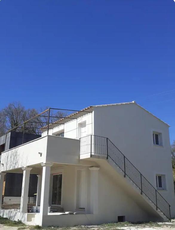 un bâtiment blanc avec un escalier sur son côté dans l'établissement Chez Lydia et Cédric, à Rochefort-du-Gard