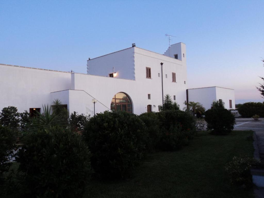 un bâtiment blanc avec un coucher de soleil en arrière-plan dans l'établissement Masseria Fabrizio, à Otrante