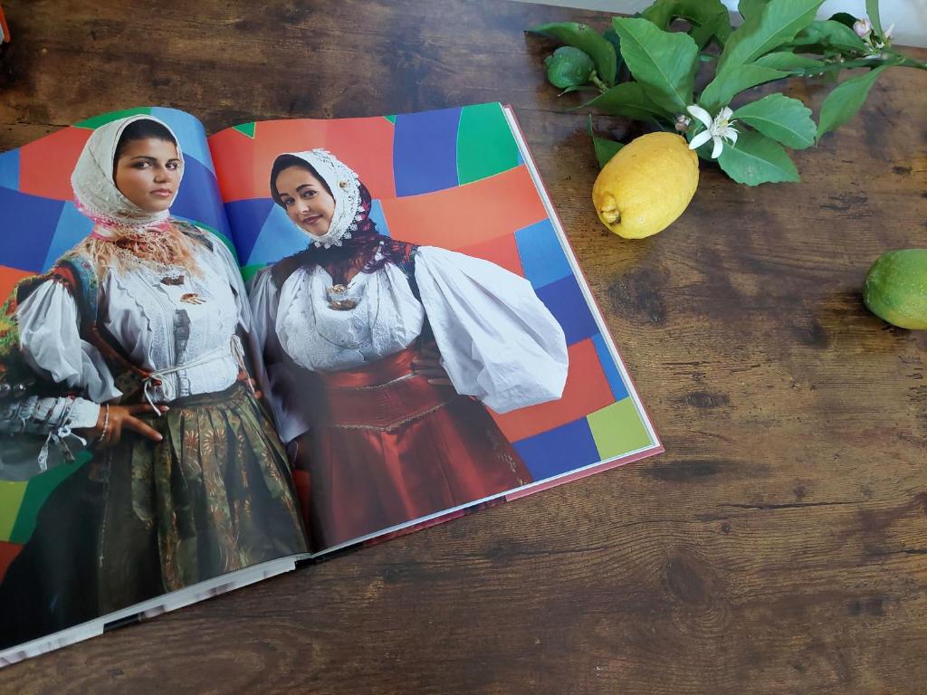 een tijdschrift met een foto van twee vrouwen op een tafel bij The Pintadera of Sardinia Iun R6887 in Carbonia