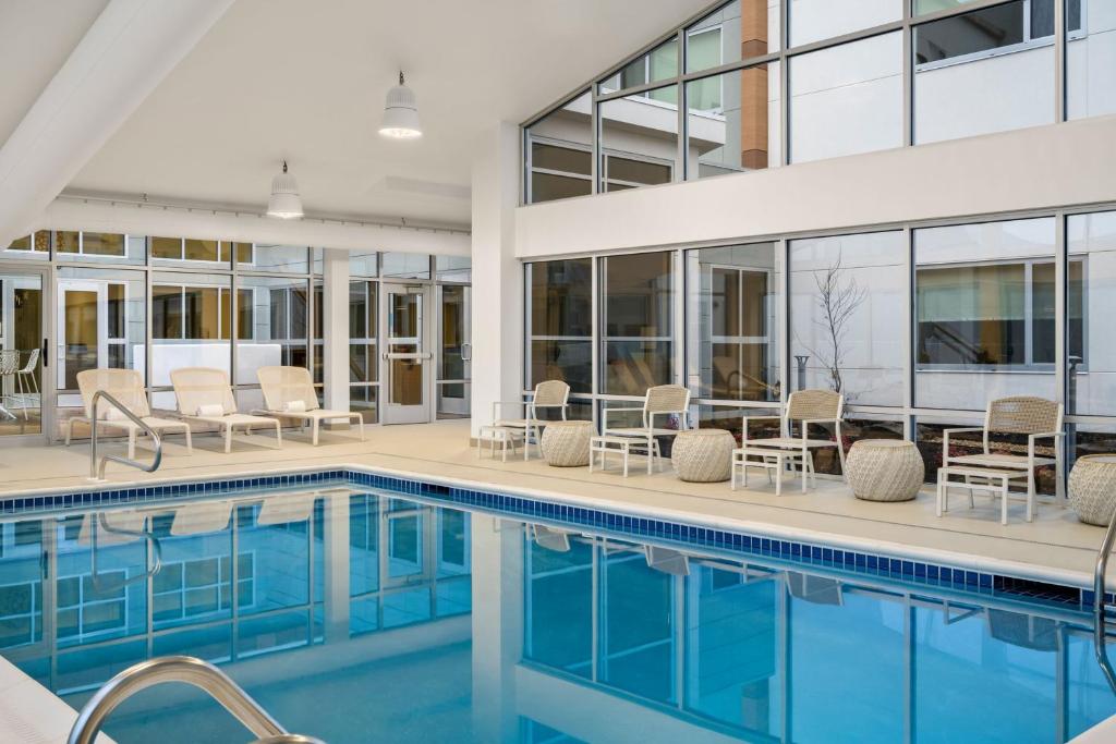 a swimming pool with chairs and tables next to a building at Element by Marriott Springfield South in Springfield