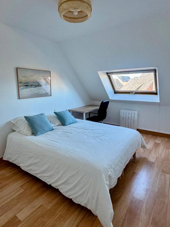 a bedroom with a large white bed and a desk at Charmante maison familiale in Ouistreham