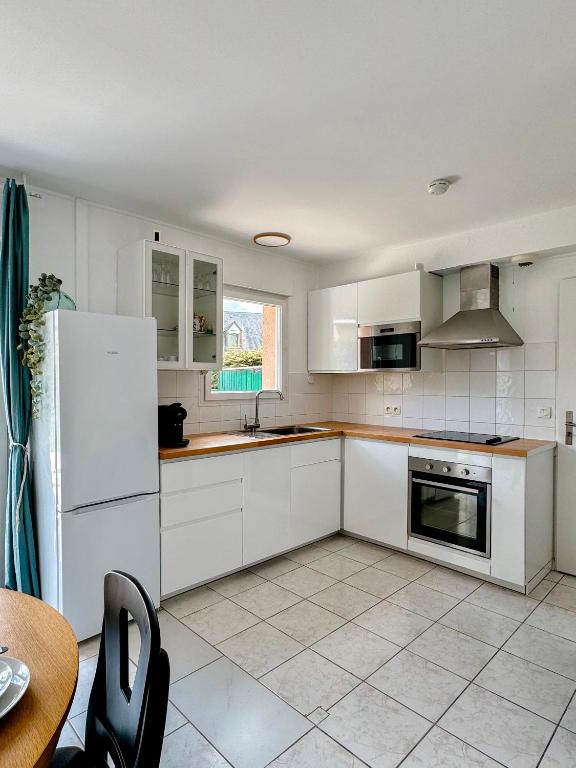 a kitchen with white cabinets and a white refrigerator at Charmante maison familiale in Ouistreham