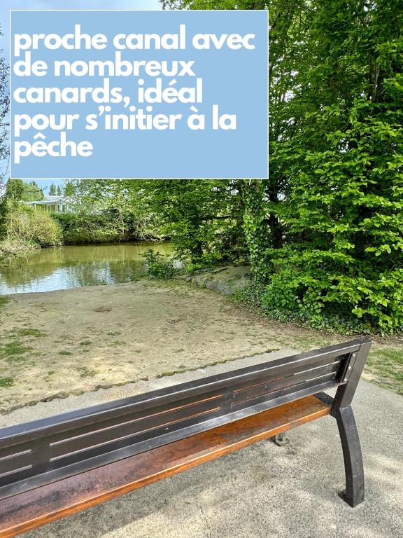a bench sitting in a park next to a pond at Charmante maison familiale in Ouistreham