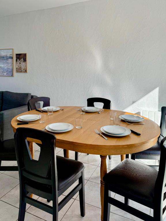 a wooden table with chairs and plates on it at Charmante maison familiale in Ouistreham