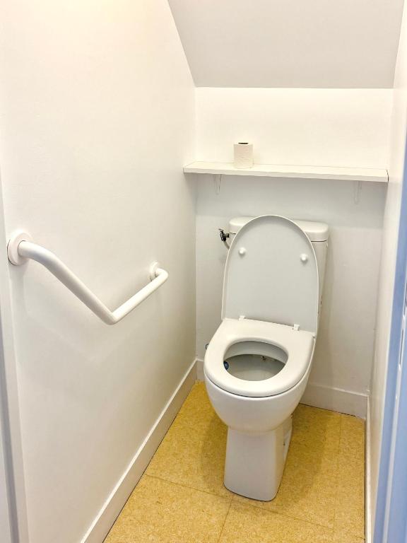 a bathroom with a toilet with a shelf on the wall at Charmante maison familiale in Ouistreham