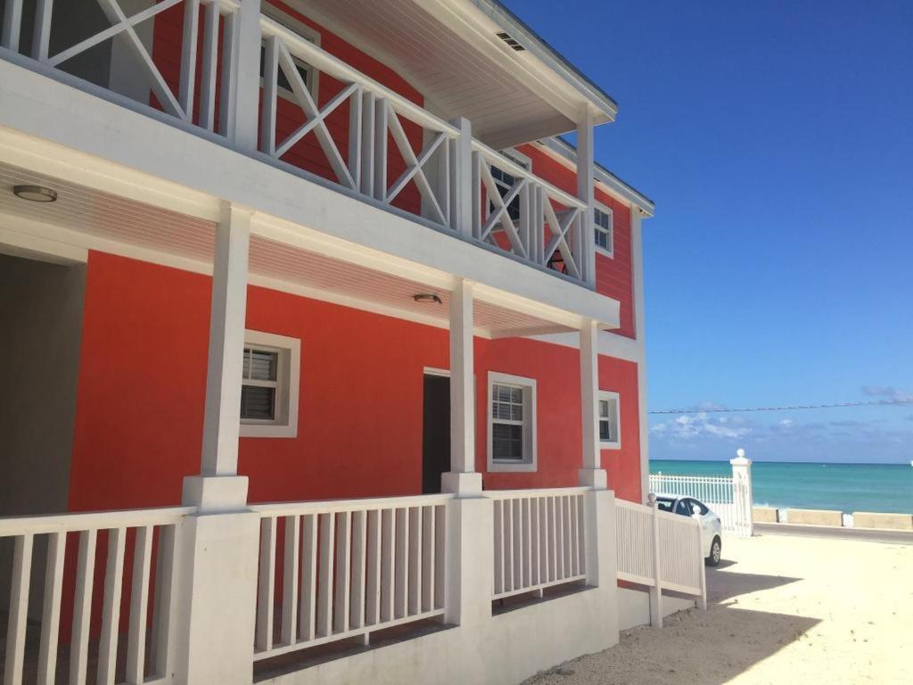 a red house with a white balcony next to the ocean at Stay BnB in Nassau