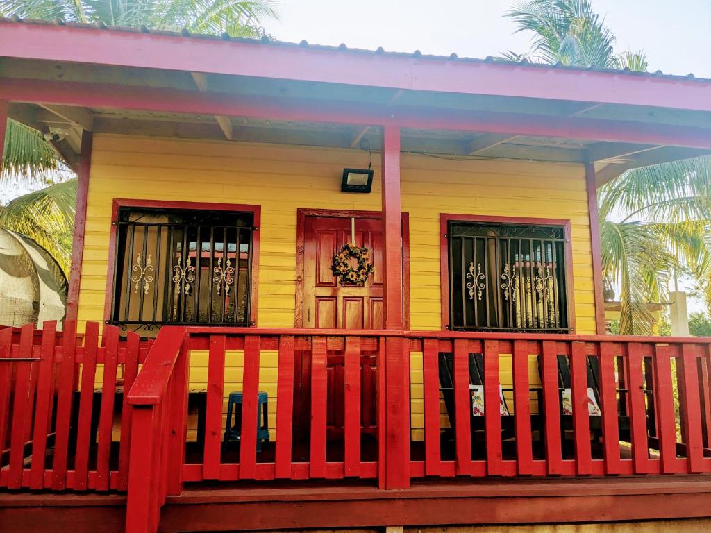 uma casa amarela e vermelha com uma cerca vermelha em Garden Cottage em San Ignacio