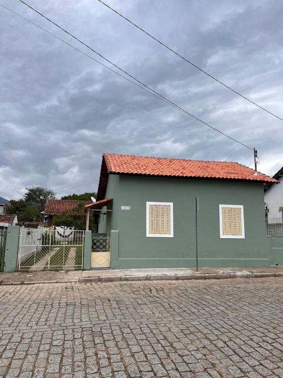 a green building with a red roof on a street at Casinha Verde in Passa Quatro