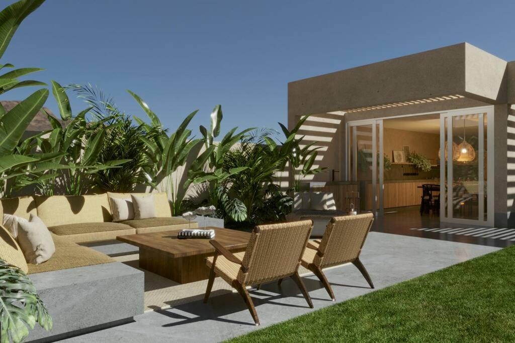 a patio with a couch and a table and chairs at Acogedora Casa en Condominio Oasis in Paracas
