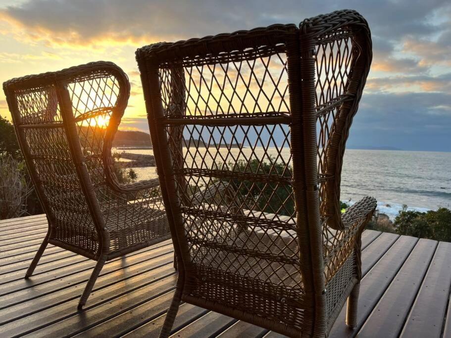 due sedie di vimini sedute su un ponte con il tramonto di The Gold Beach House a Kotoura