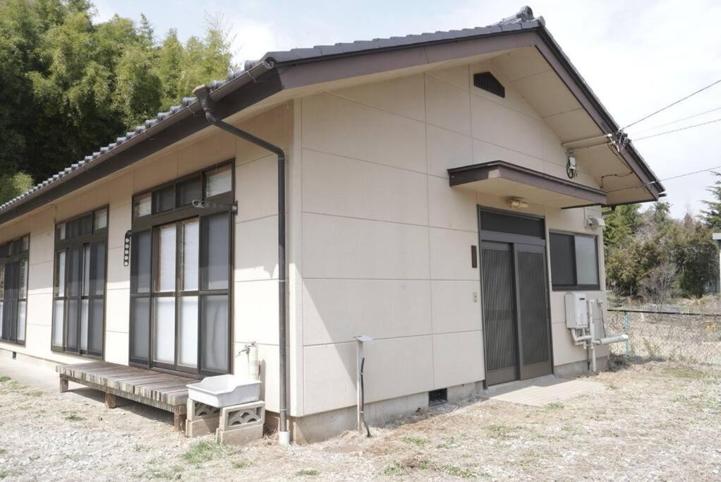 un petit bâtiment blanc avec un banc devant lui dans l'établissement 布施温泉ステイ　ウエスト, à Saku