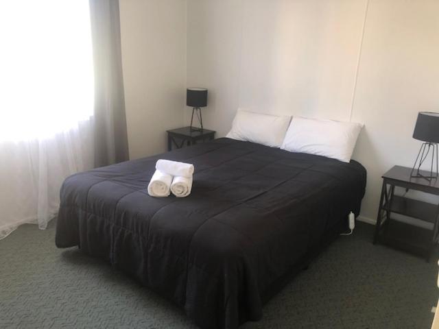 a bedroom with a large bed with two towels on it at Highlander Van Village in Armidale