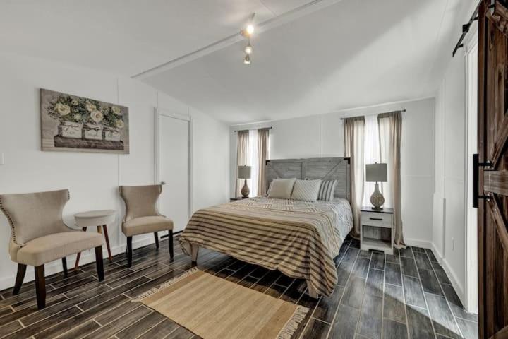 a white bedroom with a bed and two chairs at Bella’s BnB in Comfort
